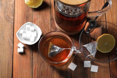 Photo of Tea bag in cup, sugar and lemon on wooden table, above view