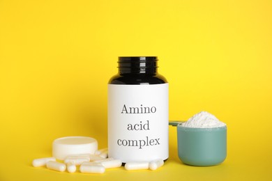 Photo of Amino acid complex, powder and pills on yellow background