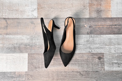 Pair of female shoes on wooden background, top view