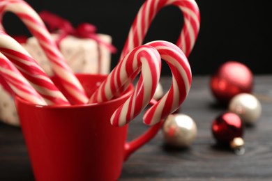 Photo of Many sweet candy canes in cup and Christmas decor on table, closeup. Space for text