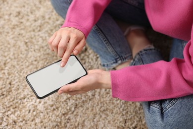 Photo of Woman using mobile phone on carpet, closeup