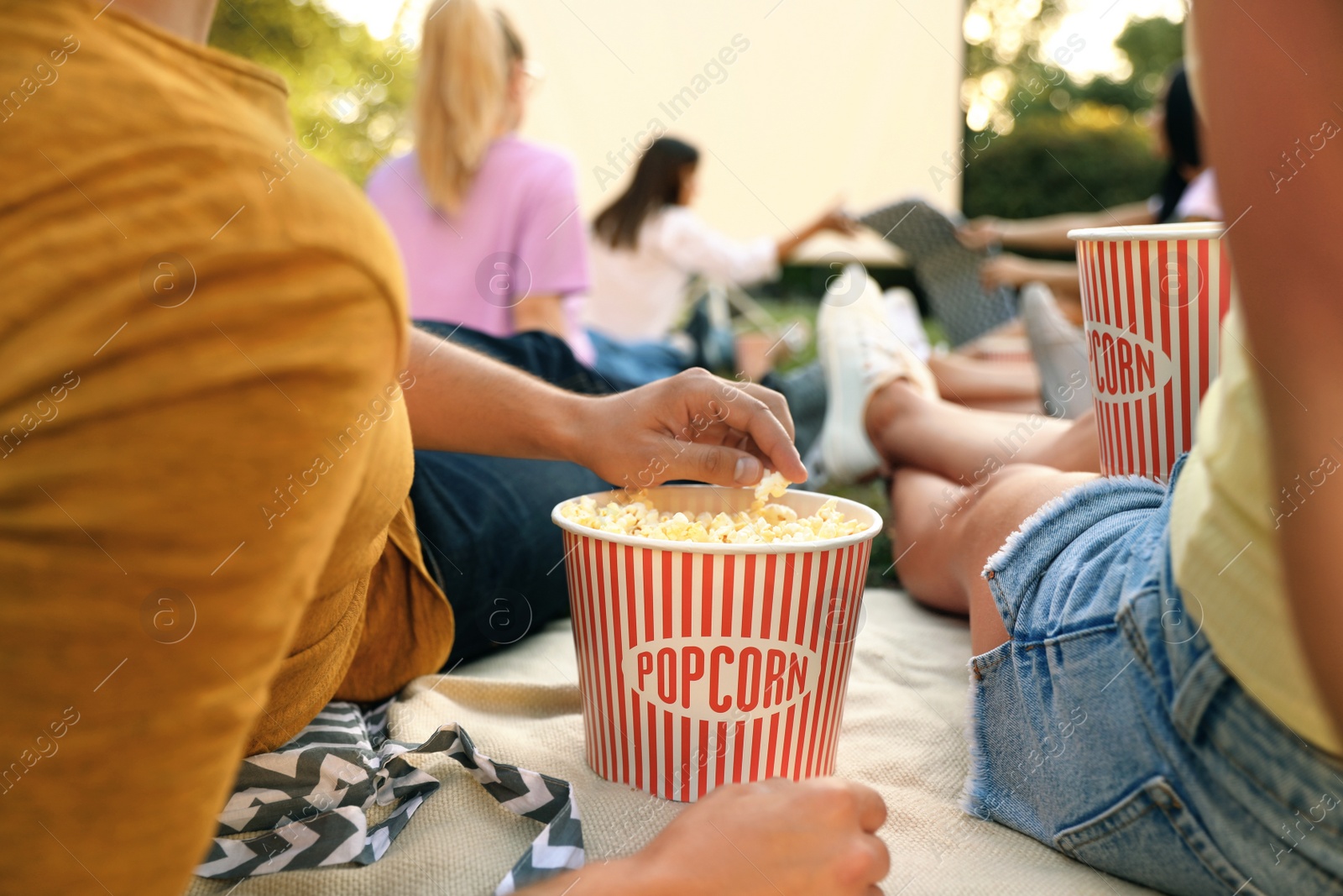 Photo of Young people with popcorn watching movie in open air cinema, closeup