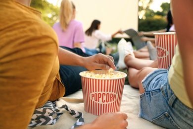 Young people with popcorn watching movie in open air cinema, closeup