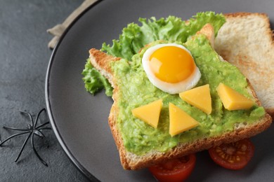 Photo of Halloween themed breakfast served on black table, closeup. Tasty sandwich with fried egg