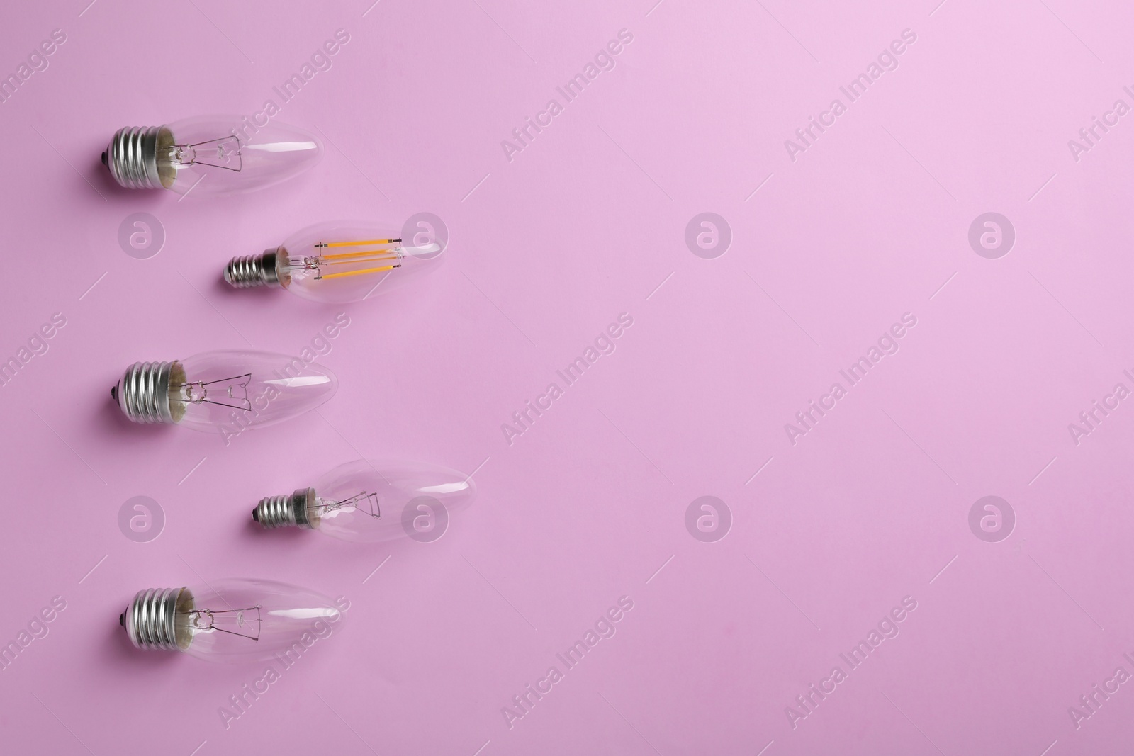 Photo of Vintage and modern lamp bulbs on pink background, flat lay. Space for text