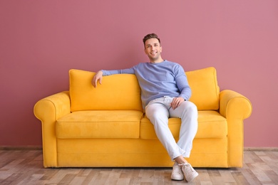 Handsome young man sitting on sofa, indoors