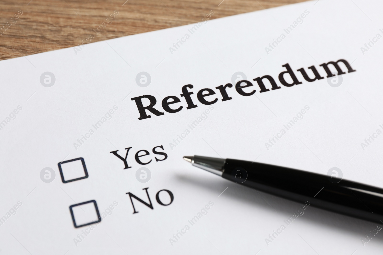 Photo of Referendum ballot with pen on wooden table, closeup