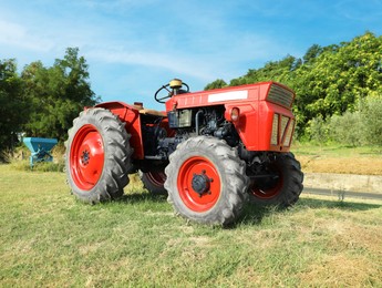 Modern tractor in mowed field on sunny day. Agricultural industry