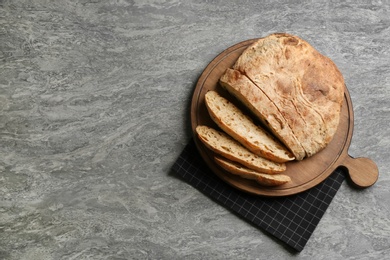 Photo of Tasty freshly baked bread on grey table, top view. Space for text