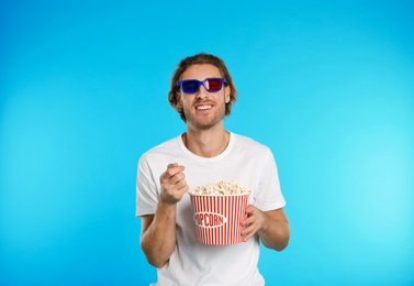Photo of Man with 3D glasses and popcorn during cinema show on color background