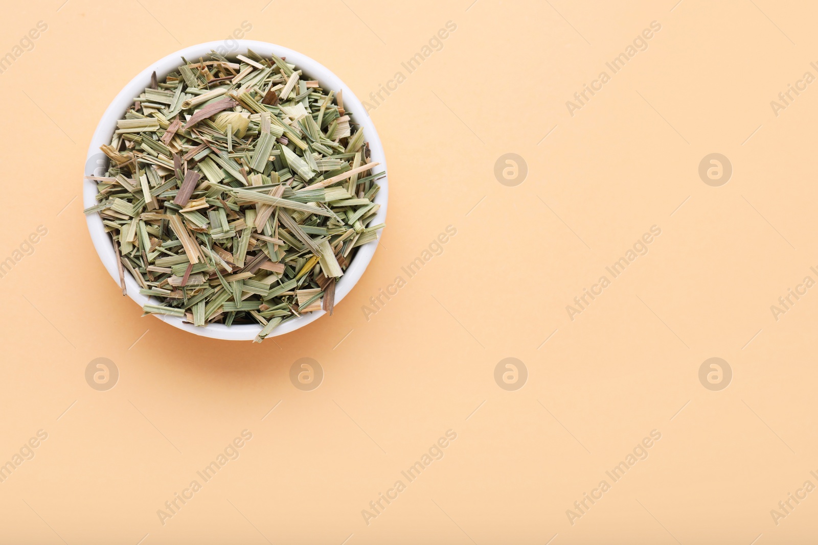 Photo of Bowl with aromatic dried lemongrass on beige background, top view. Space for text