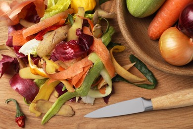 Different fresh vegetables with peels and knife on wooden table,top view