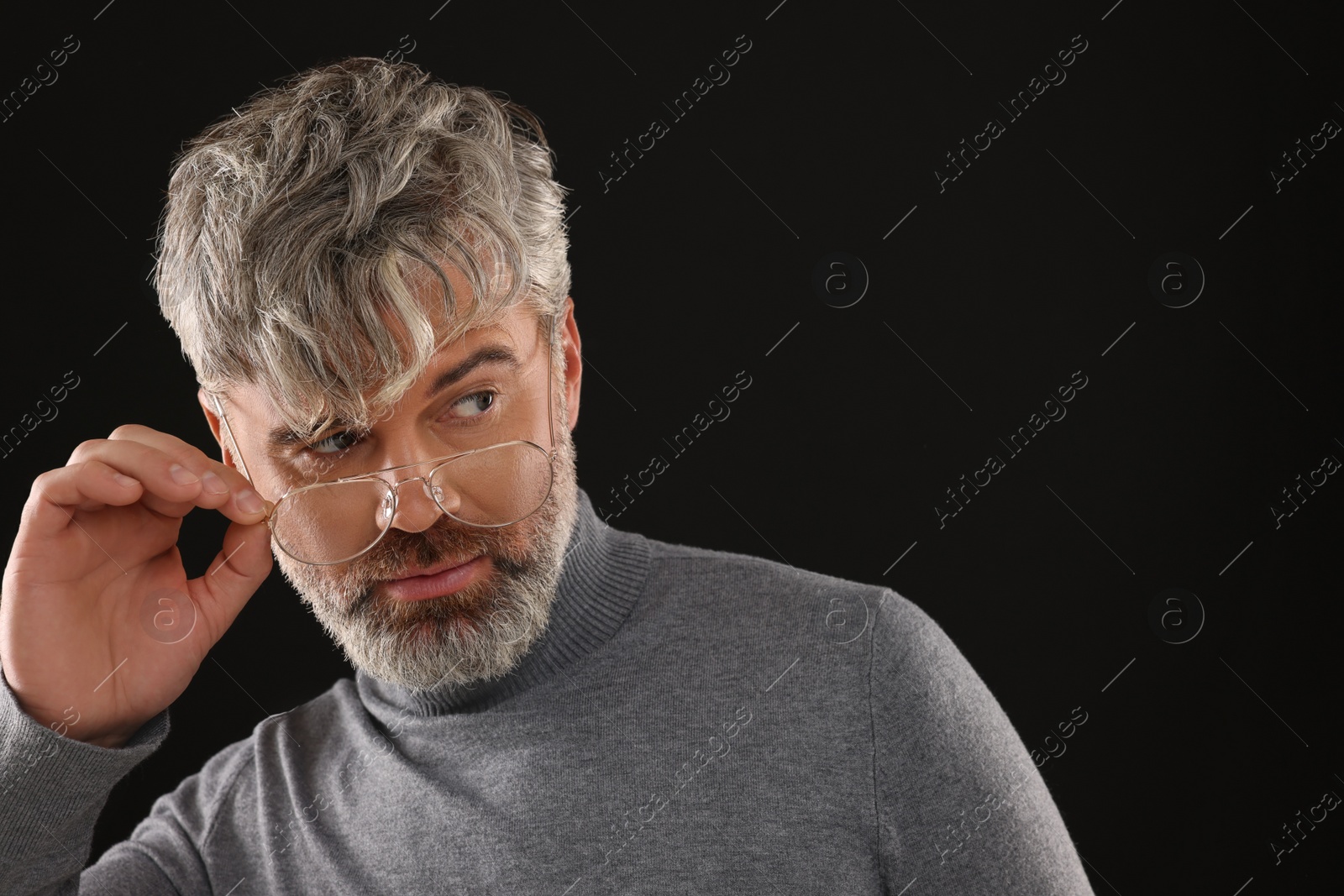 Photo of Portrait of confident man with beautiful hairstyle on black background. Space for text