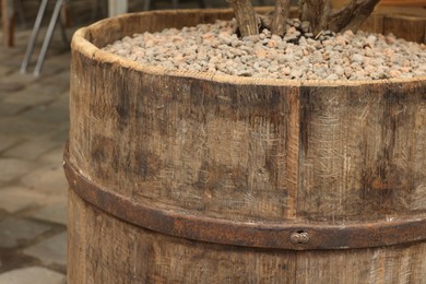 Photo of Traditional wooden barrel with gravel outdoors, closeup