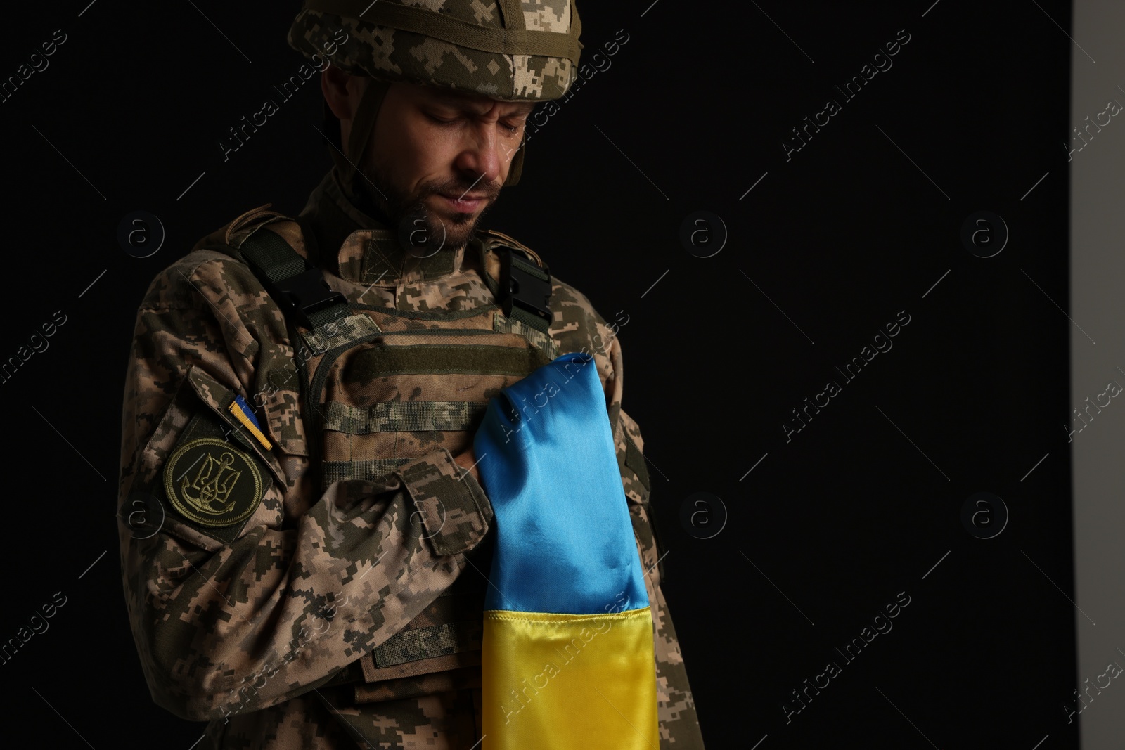 Photo of Soldier in military uniform with Ukrainian flag on black background