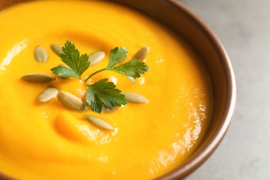 Photo of Delicious pumpkin cream soup with seeds and parsley in bowl, closeup