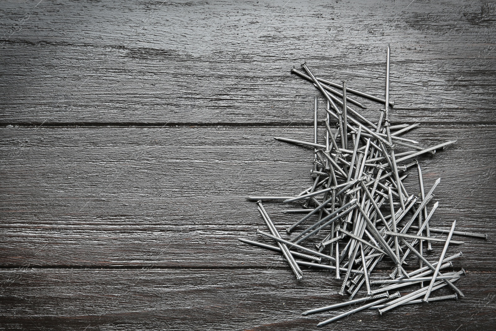 Photo of Many metal nails on wooden background, flat lay. Space for text