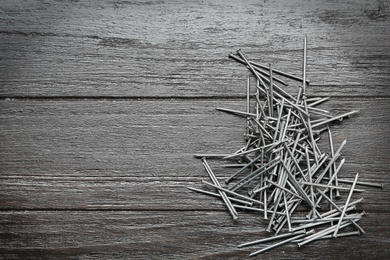 Photo of Many metal nails on wooden background, flat lay. Space for text