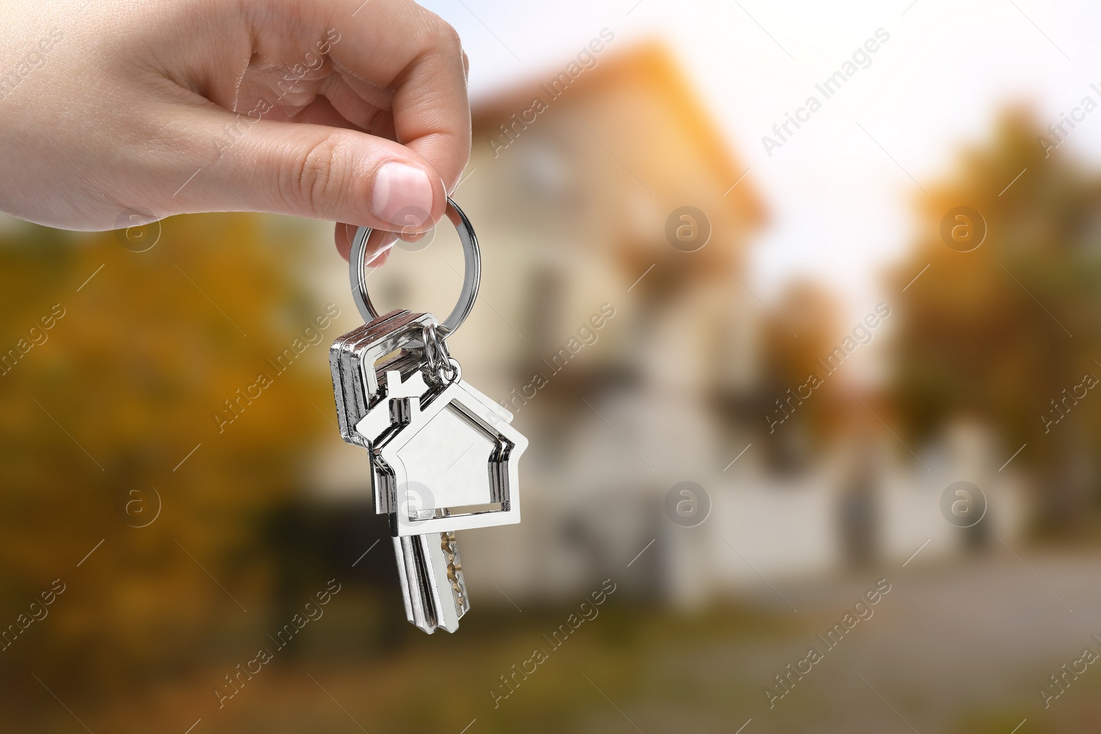 Image of Woman holding keys near house outdoors, closeup