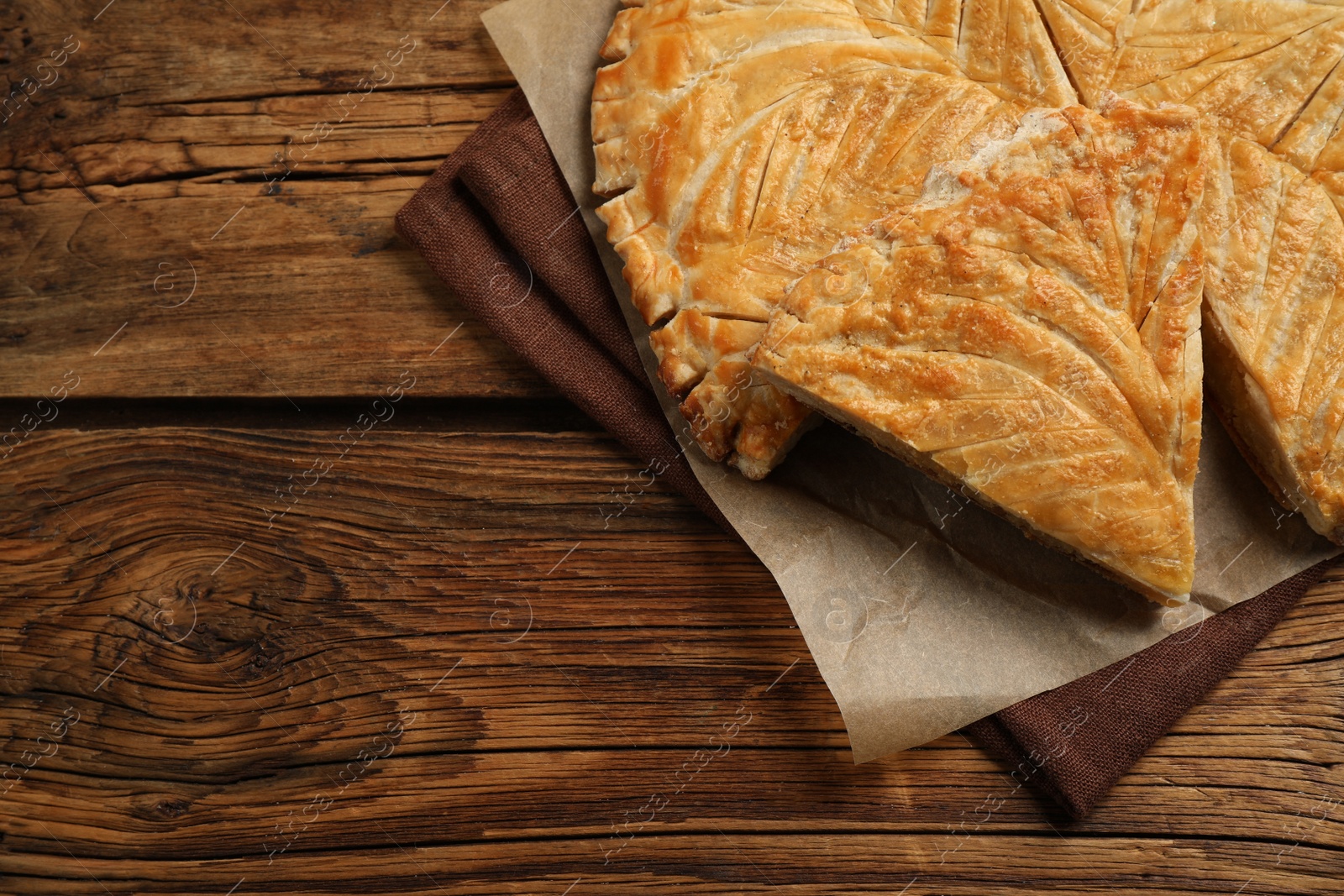 Photo of Traditional galette des Rois on wooden table, above view. Space for text