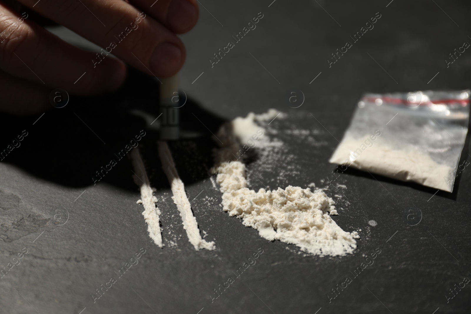 Photo of Addicted man with hard drug and rolled dollar banknote preparing for consumption at grey textured table, closeup