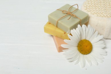 Bars of soap and and chamomile on white wooden table. Space for text