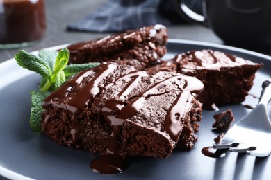 Photo of Delicious chocolate brownies with sweet syrup and mint on plate, closeup