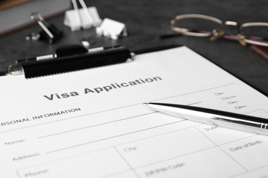 Photo of Visa application form for immigration and pen on grey table, closeup