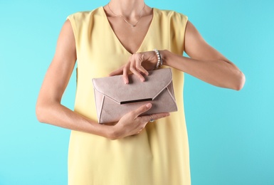 Young woman in stylish outfit with purse on color background, closeup