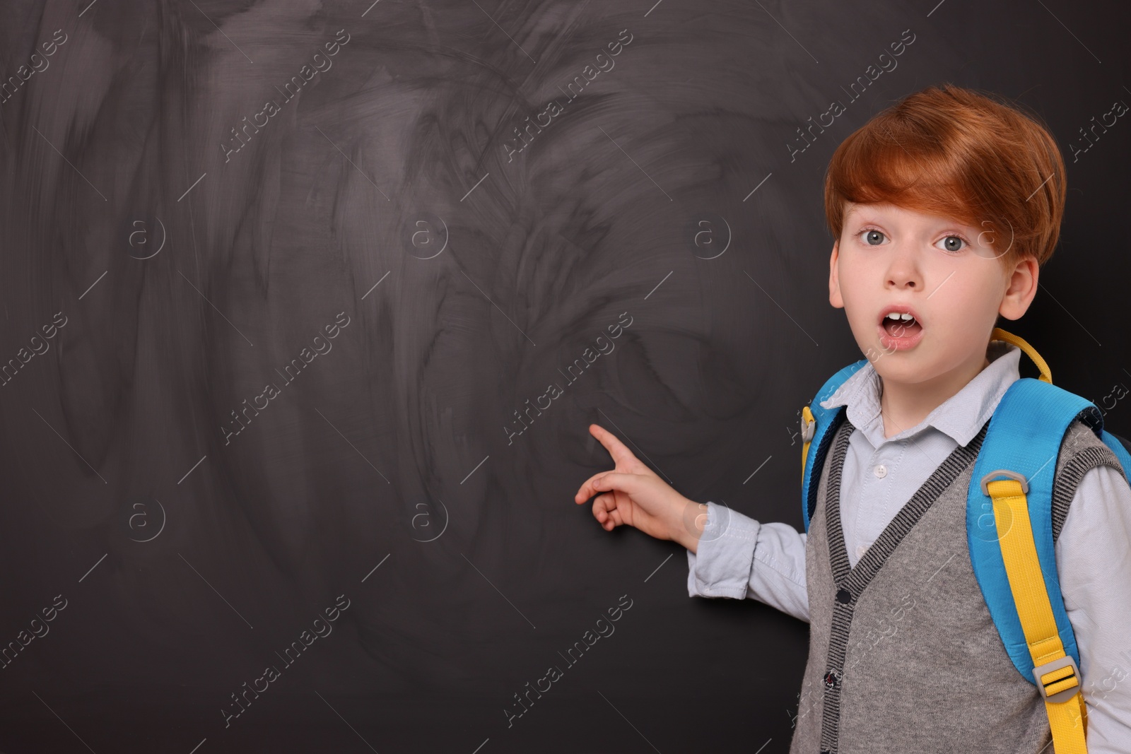 Photo of Shocked schoolboy pointing at something on blackboard. Space for text