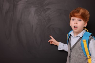 Photo of Shocked schoolboy pointing at something on blackboard. Space for text