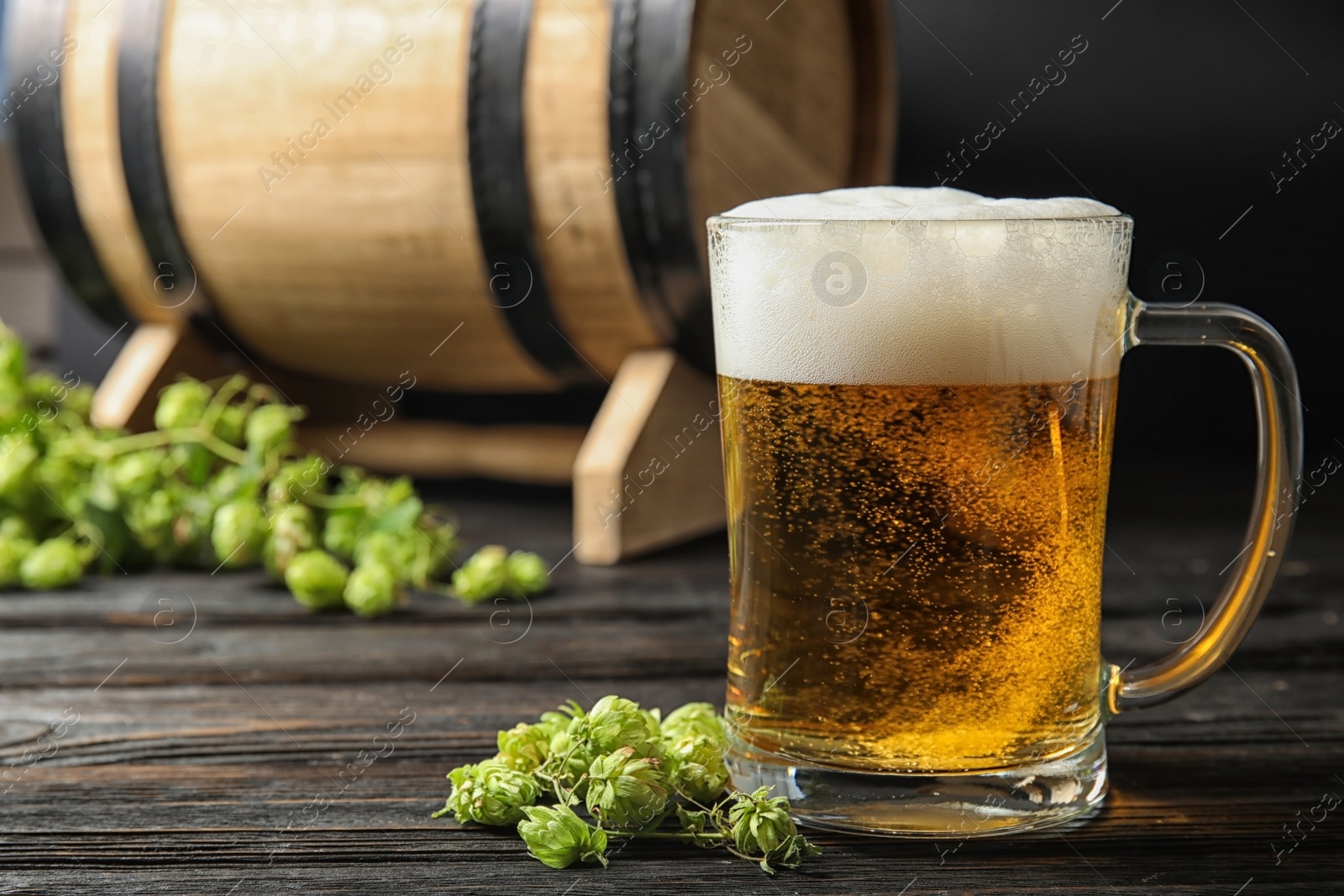 Photo of Composition with tasty beer and fresh green hops on wooden table. Space for text