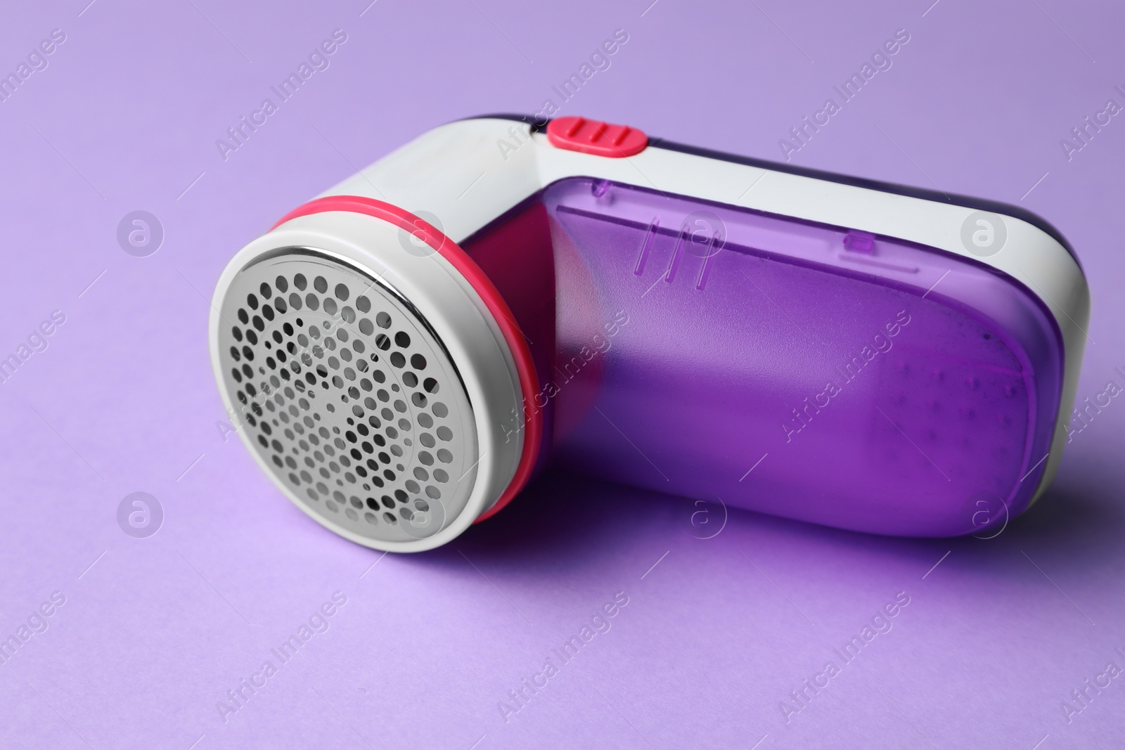Photo of Modern fabric shaver for lint removing on purple background