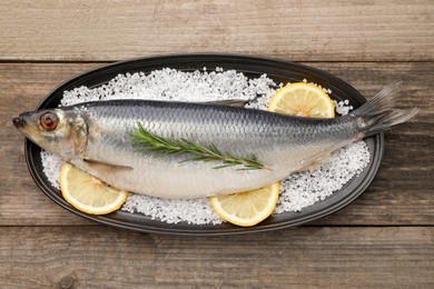 Photo of Plate with salted herring, rosemary and lemon on wooden table, top view