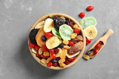 Photo of Bowl and scoop with different dried fruits on grey background, top view. Healthy lifestyle
