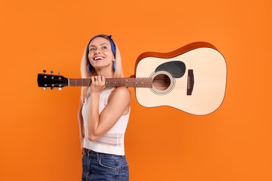 Photo of Happy hippie woman with guitar on orange background