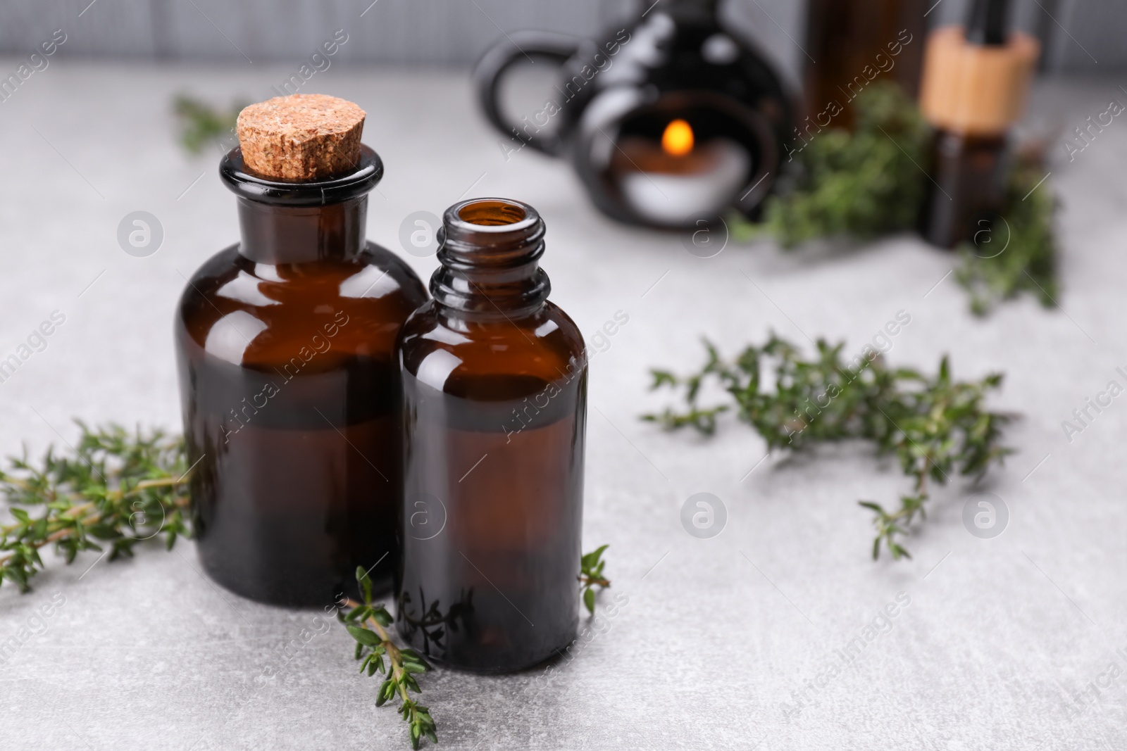 Photo of Thyme essential oil on light grey table, space for text