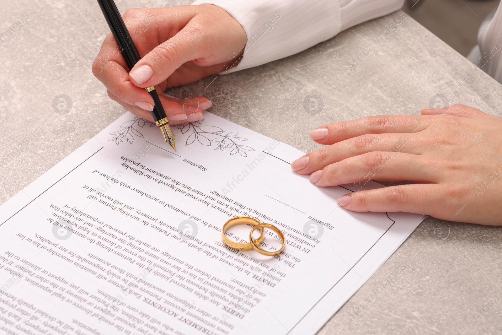 Photo of Woman signing marriage contract at light grey table, closeup