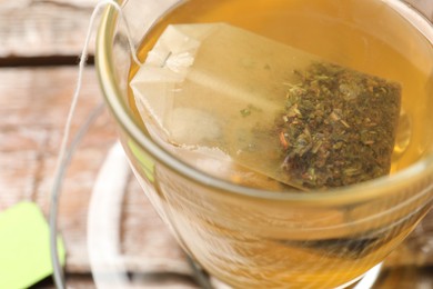 Tea bag in glass cup on table, closeup