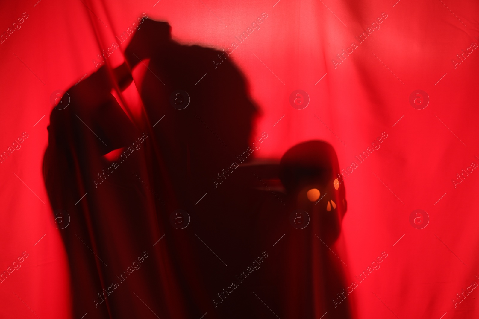 Photo of Silhouette of creepy ghost with skull behind red cloth, space for text