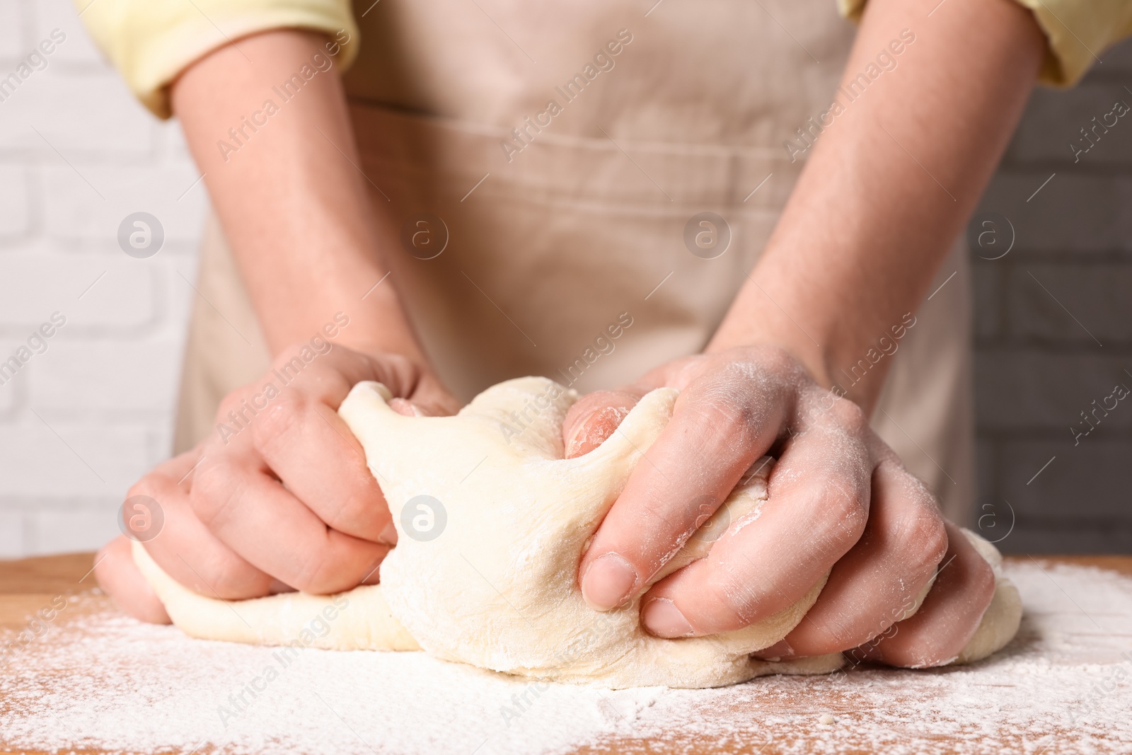 Photo of Woman kneading dough at wooden table, closeup