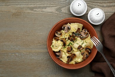Photo of Delicious ravioli with mushrooms served on wooden table, flat lay. Space for text