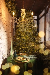 Beautiful festive table setting near Christmas tree with decor in room
