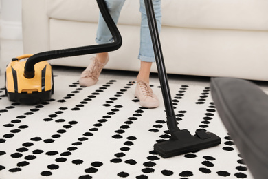 Young woman using vacuum cleaner at home, closeup