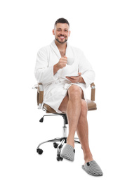 Photo of Handsome man with cup of coffee wearing bathrobe sitting in chair on white background