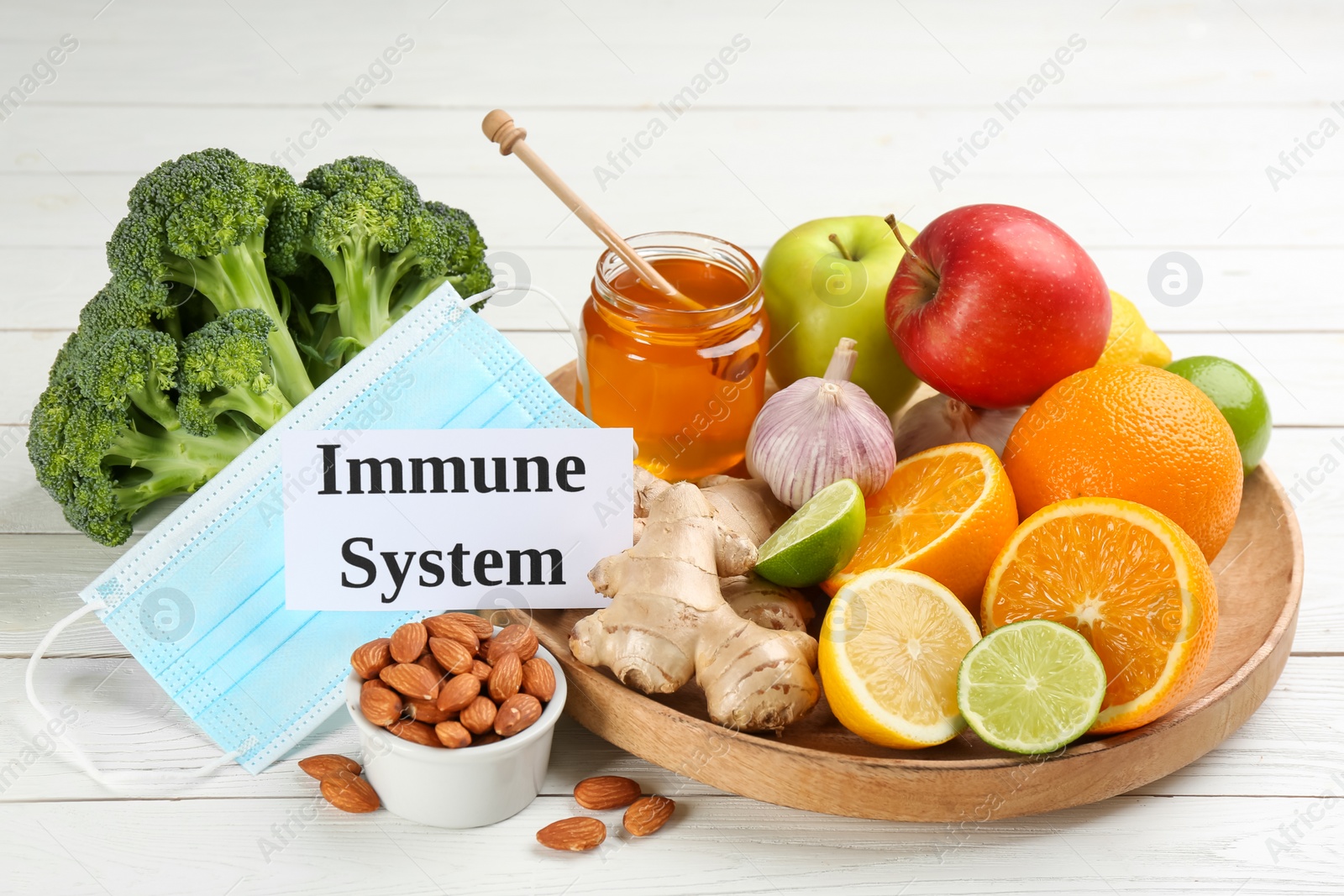 Photo of Card with phrase Immune System, medical mask and fresh products on white wooden table