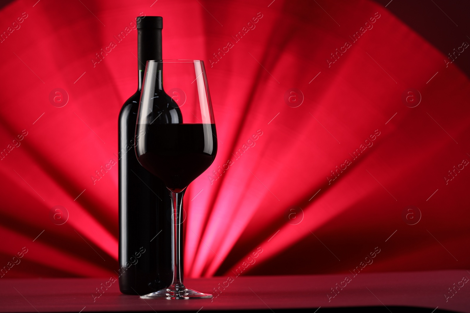 Photo of Stylish presentation of delicious red wine in bottle and glass on color background. Space for text