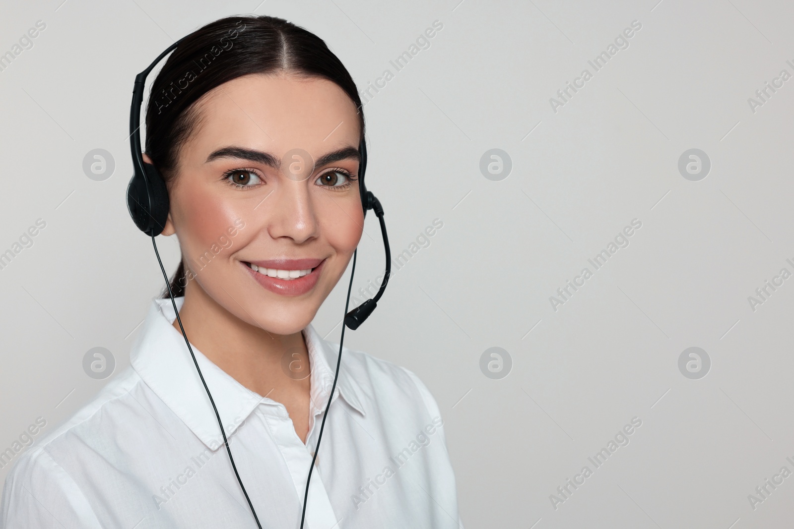 Photo of Hotline operator with modern headset on light grey background, space for text. Customer support