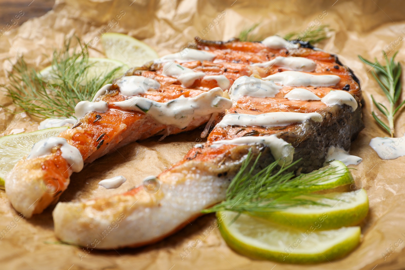 Photo of Tasty salmon steak with sauce, citrus slices and dill on parchment paper, closeup