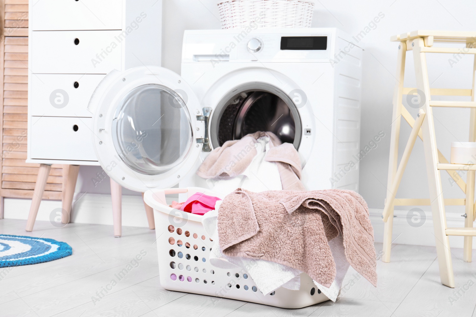 Photo of Basket with dirty towels in laundry room